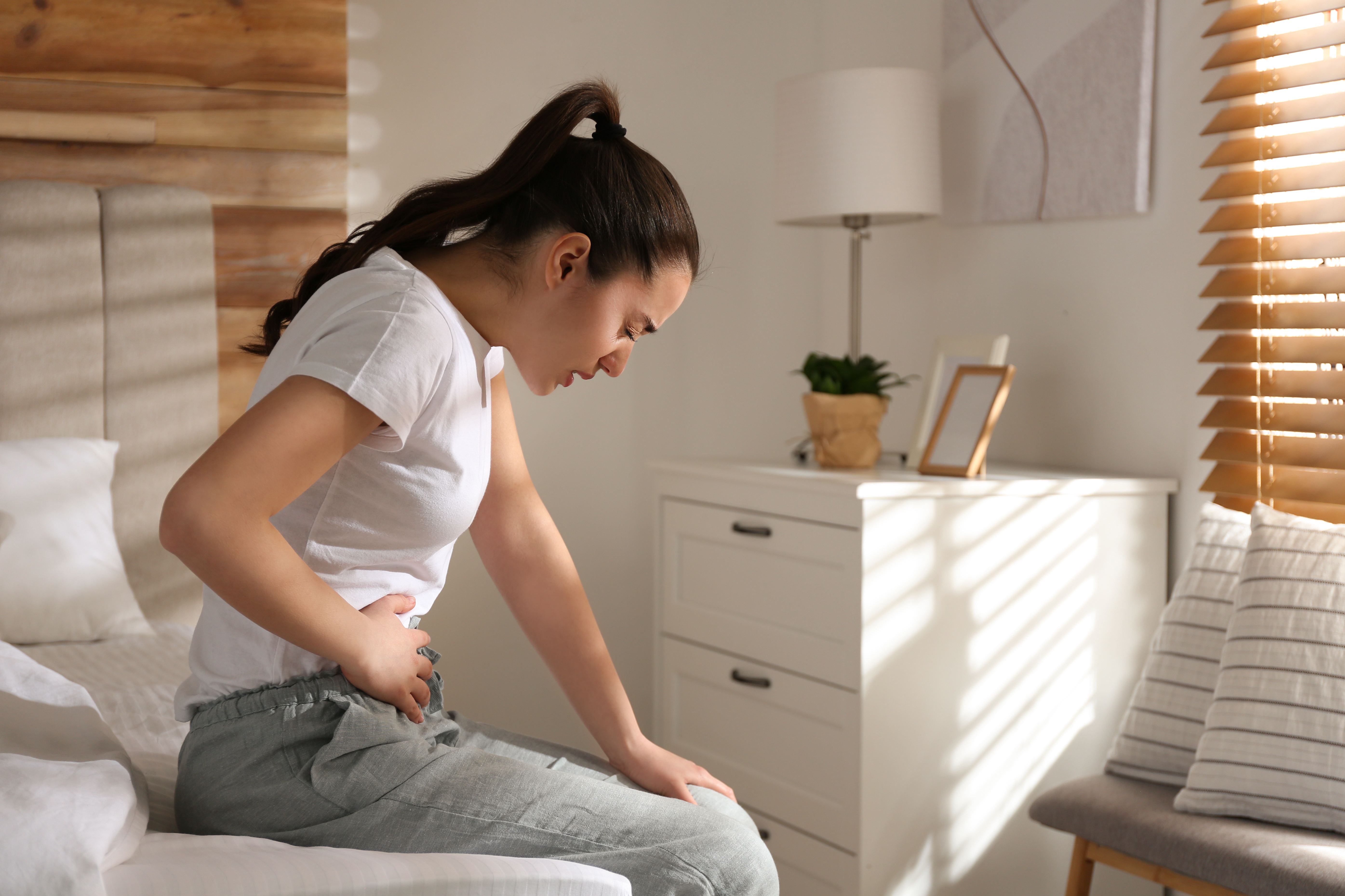 Pregabalin Entzugserscheinung: Frau mit Bauchkrämpfen hält sich ihren Bauch