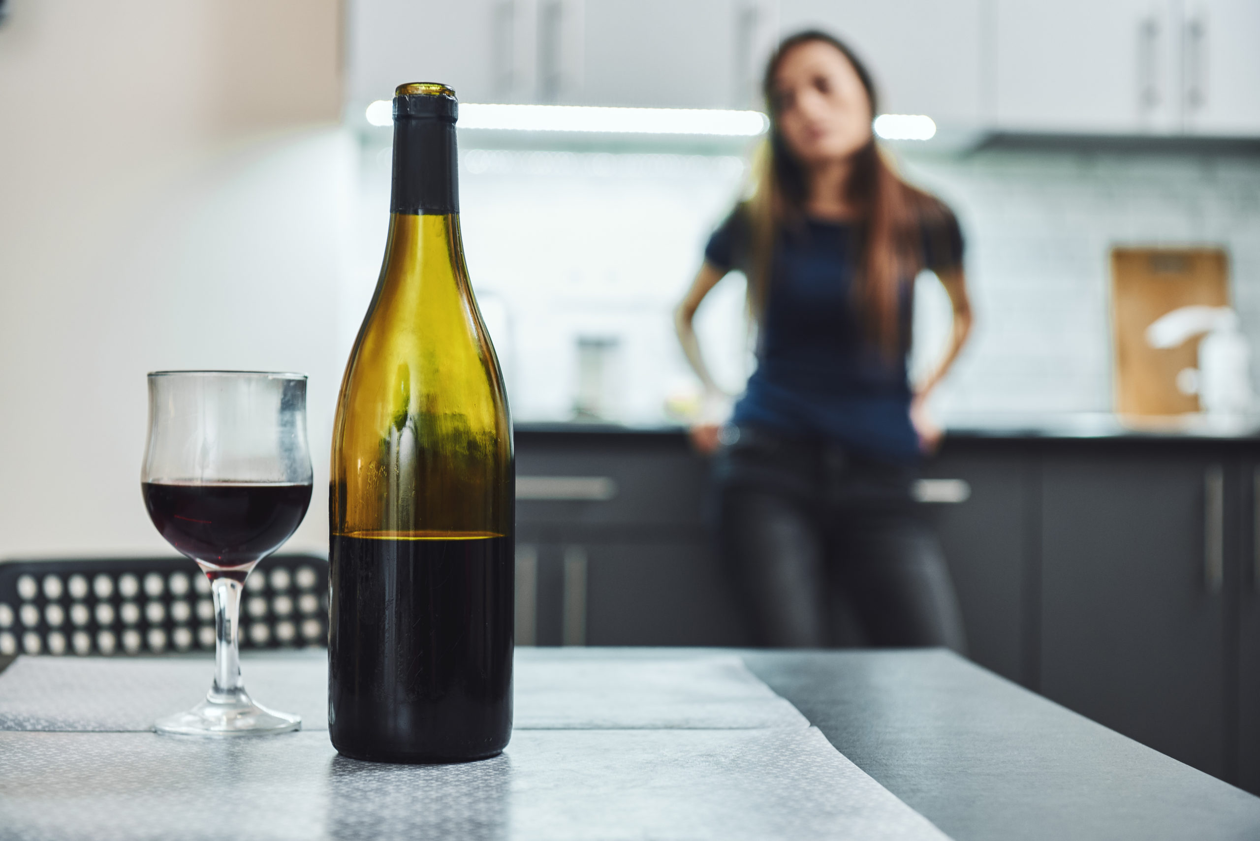 Alkohol trinken mit Depression: Frau steht vor geöffnetem Wein