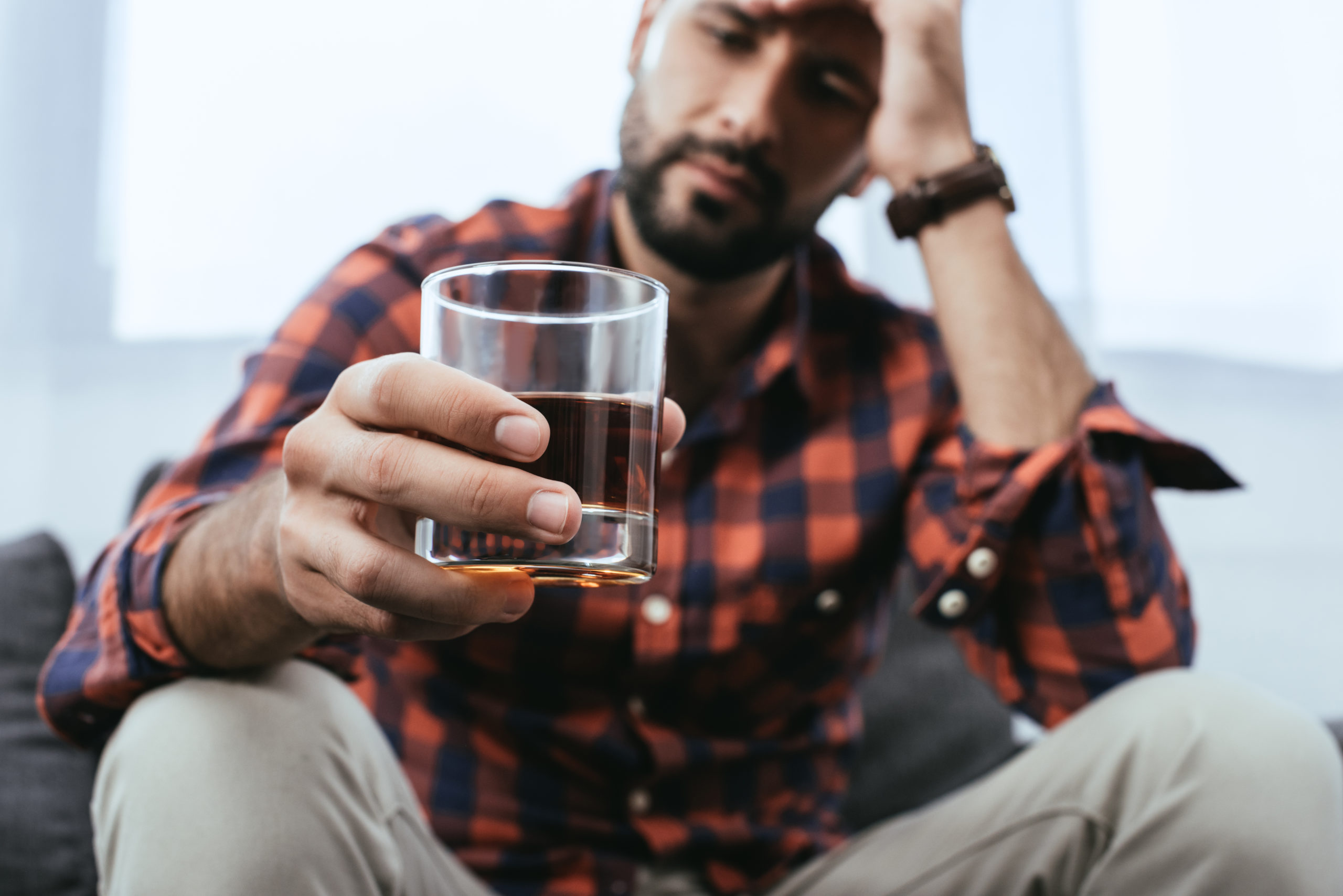 Mann mit Glas hinterfragt Alkoholkonsum