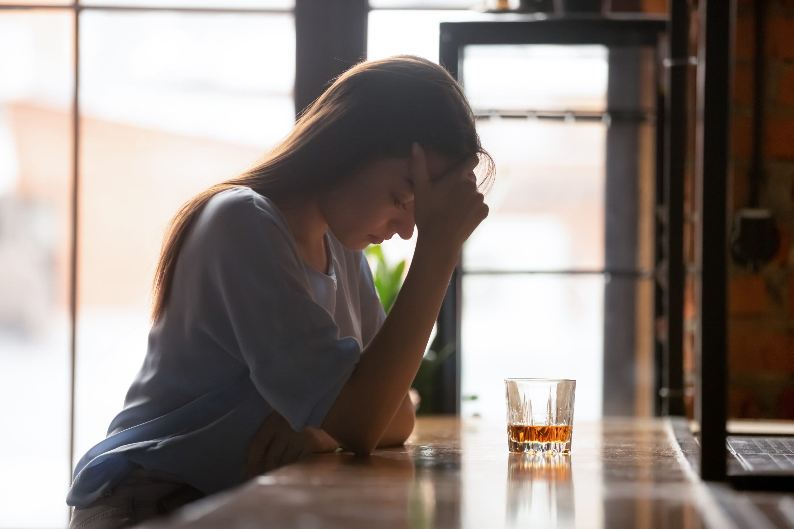 Junge traurige Frau in Bar mit Alkohol