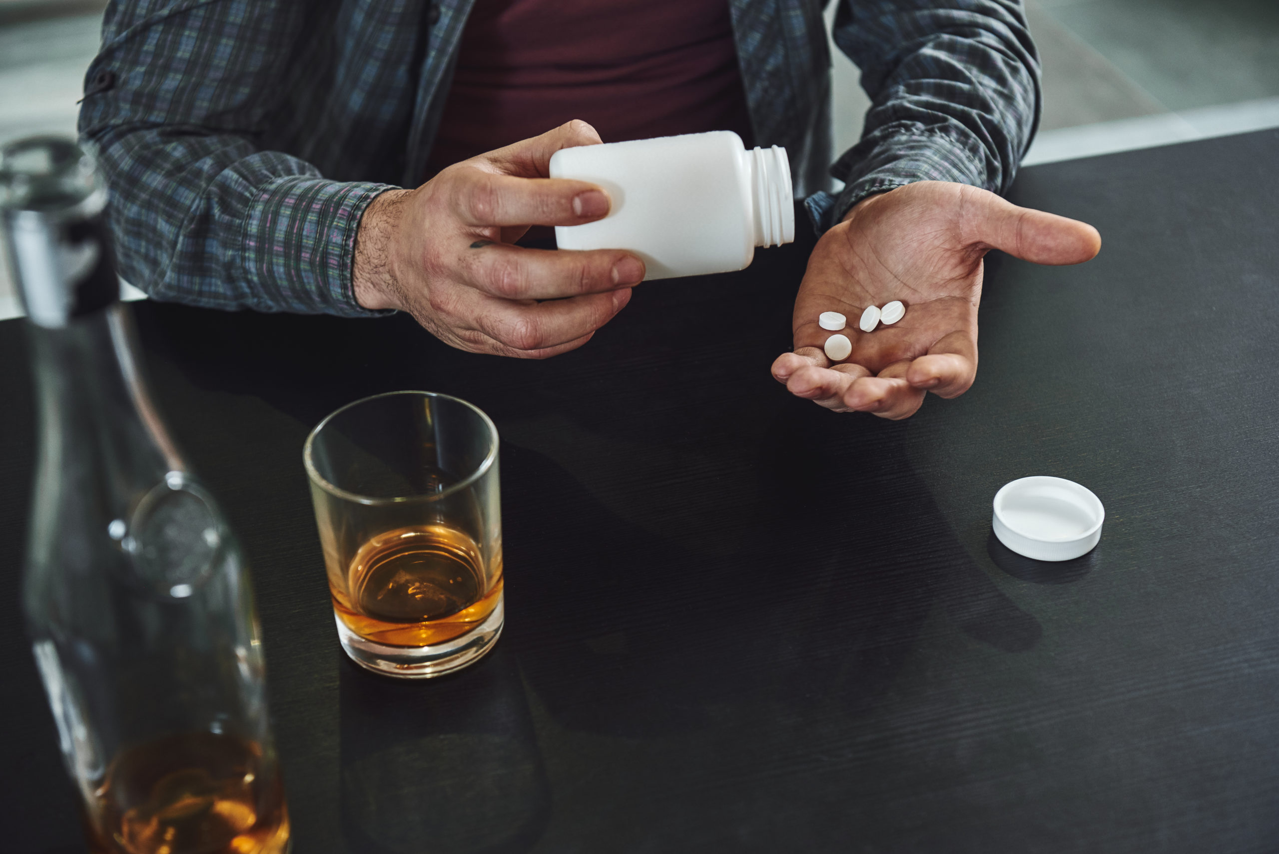Wechselwirkungen von Alkohol und Medikamente: Mann mit Alkohol und Tabletten